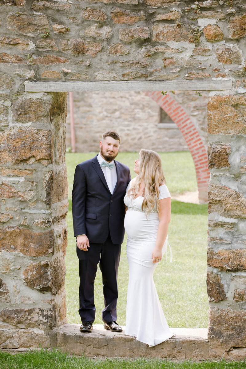 Bride and  groom standing in an opening in a stone wall