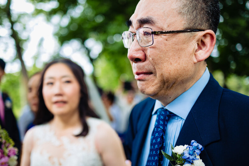 Father of the bride walking his daughter down the aisle as a huge tear rolls down his face barely keeping it together