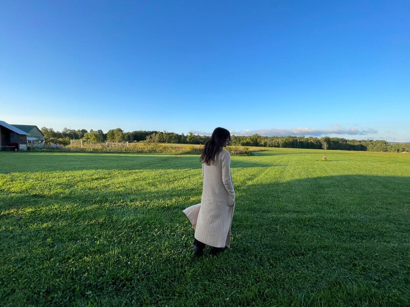 A woman in a green field enjoys moments of solitude
