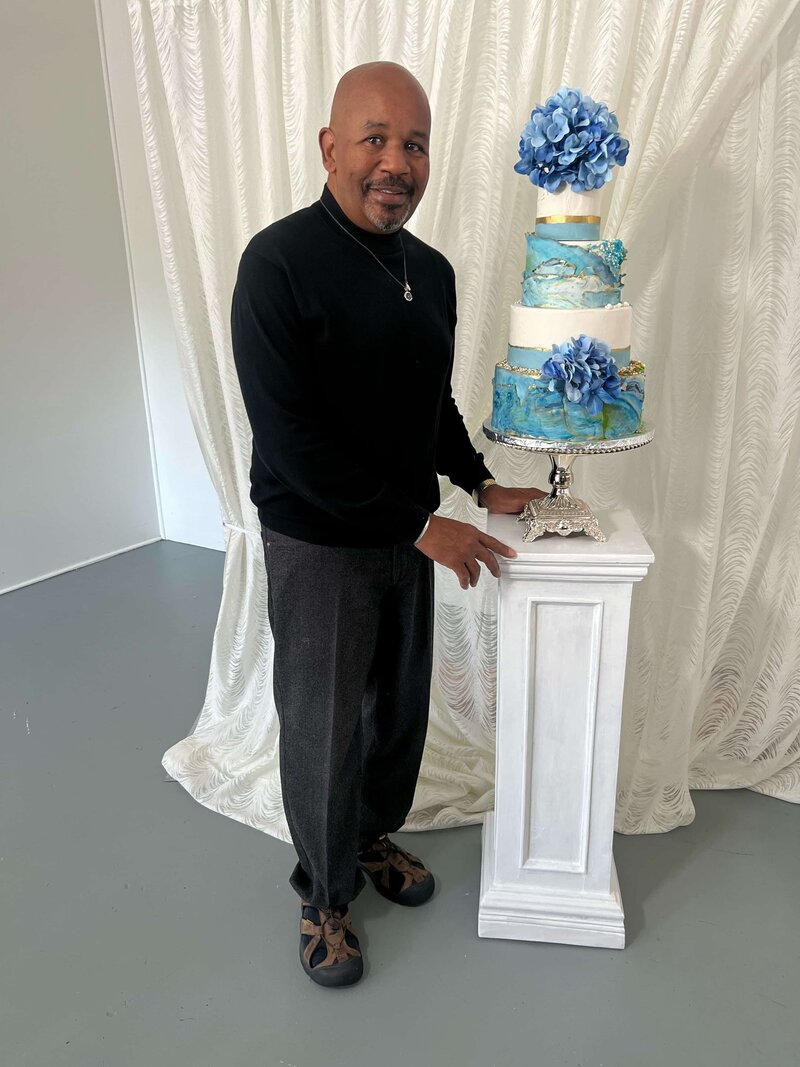 Wedding planner standing next to blue and white wedding cake