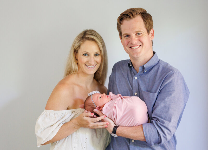 Couple smiling and holding a newborn baby girl
