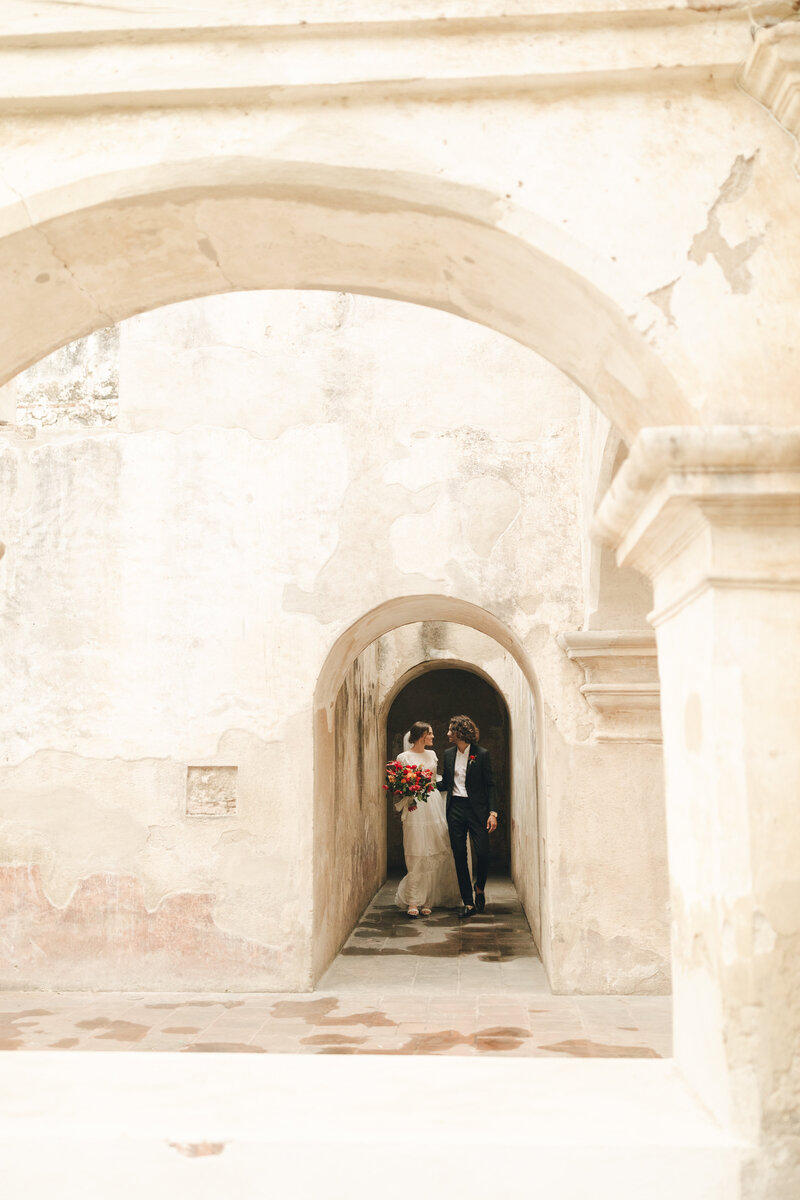 bride and groom walking down stone hallway