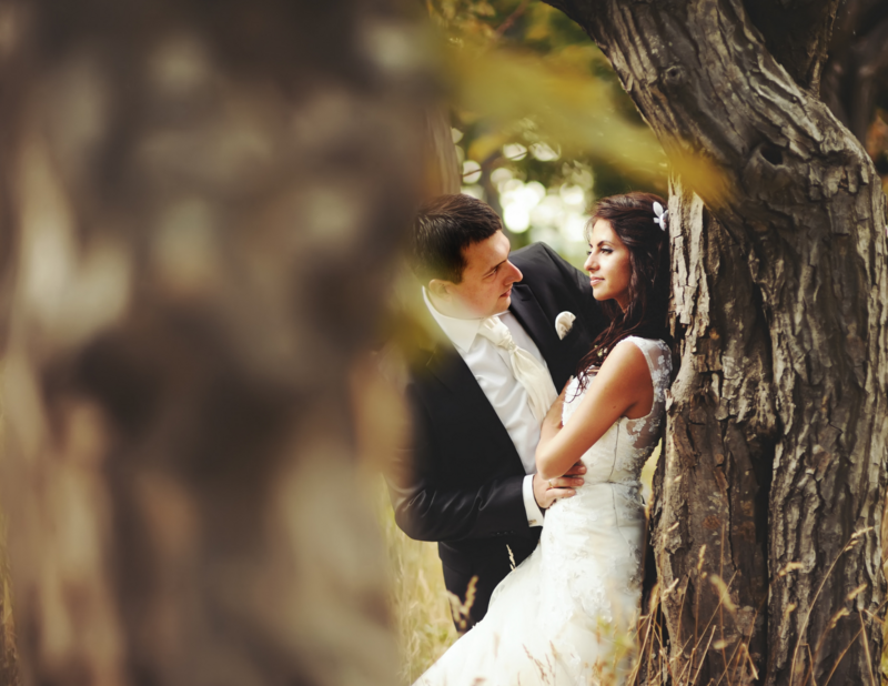 Bride leaning against a tree