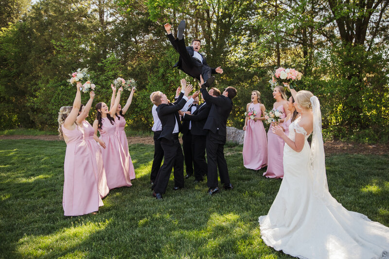 groom being tossed in the air surrounded by bridal party