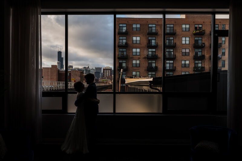 Couple is silhouetted against the chicago skyline at The Mae District in Chicago, IL.