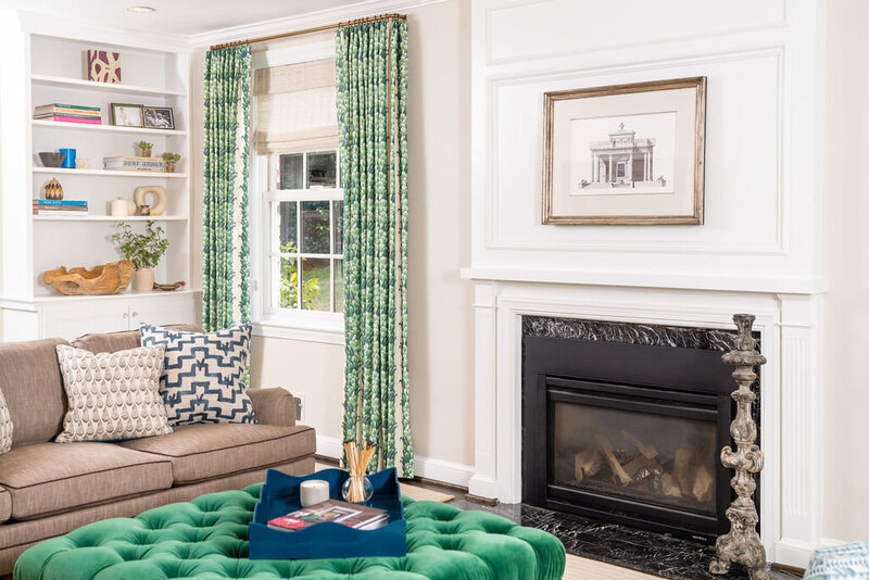 Bold living room with beige couches, green velvet ottoman and patterned artwork