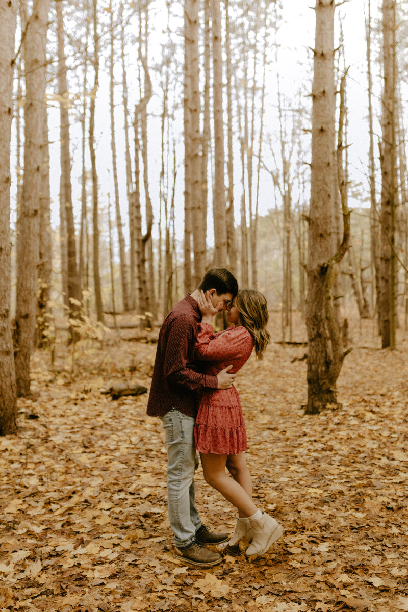Couple hugging during their engagement pictures in the woods