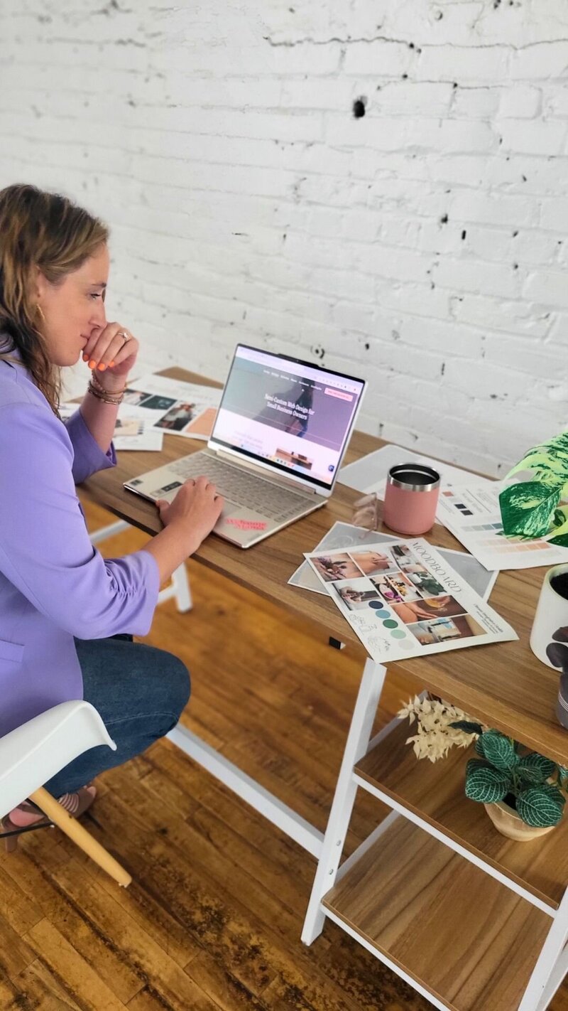 Julie Wenzlick working on SEO strategy at laptop with coffee and brand materials on desk