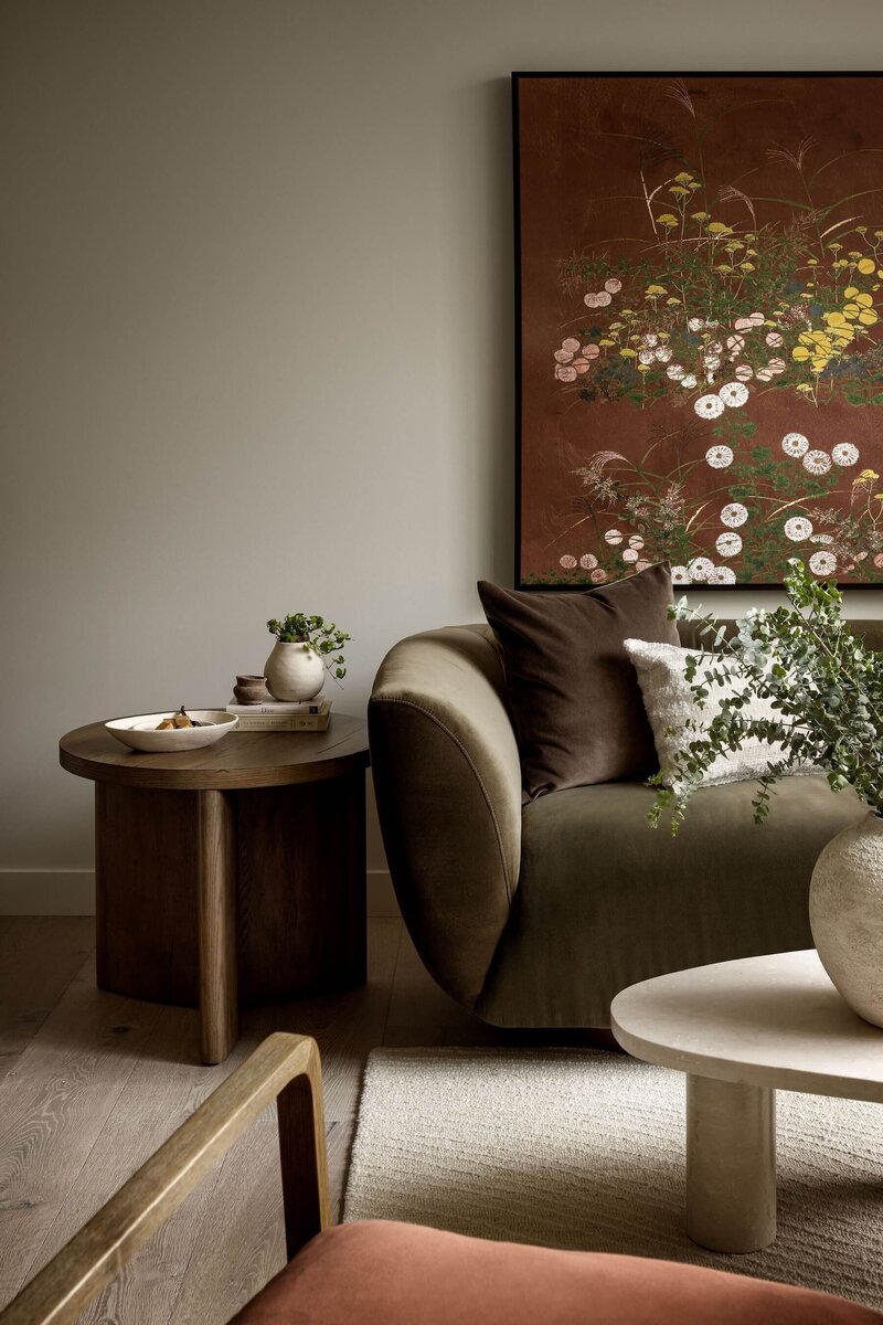 Modern Japandi living space featuring an olive green sofa and abstract floral artwork in warm rust and earthy hues.