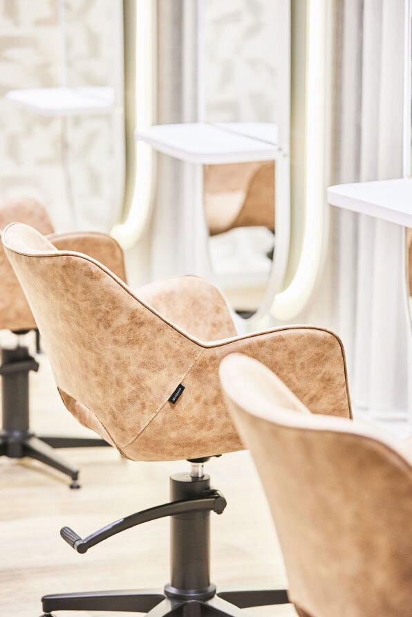 Modern salon interior featuring beige styling chairs and illuminated mirrors at a Neutral Bay hair salon.