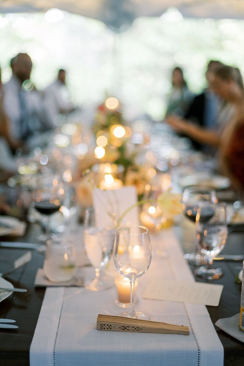 Long rectangular reception tables with bud vases, candles and wine glasses