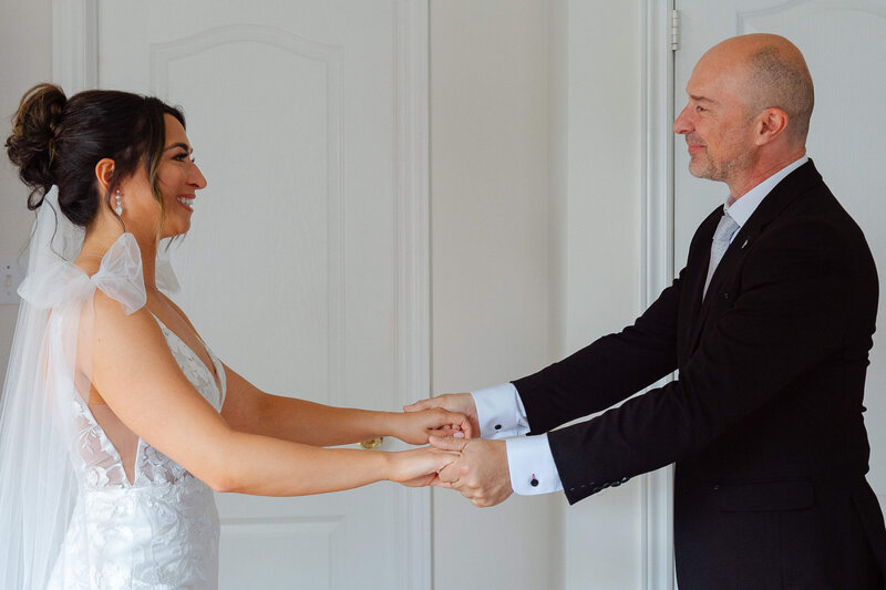 a bride holds hands with her father as he sees her for the first time.  Taken by Ottawa wedding photographer JEMMAN Photography