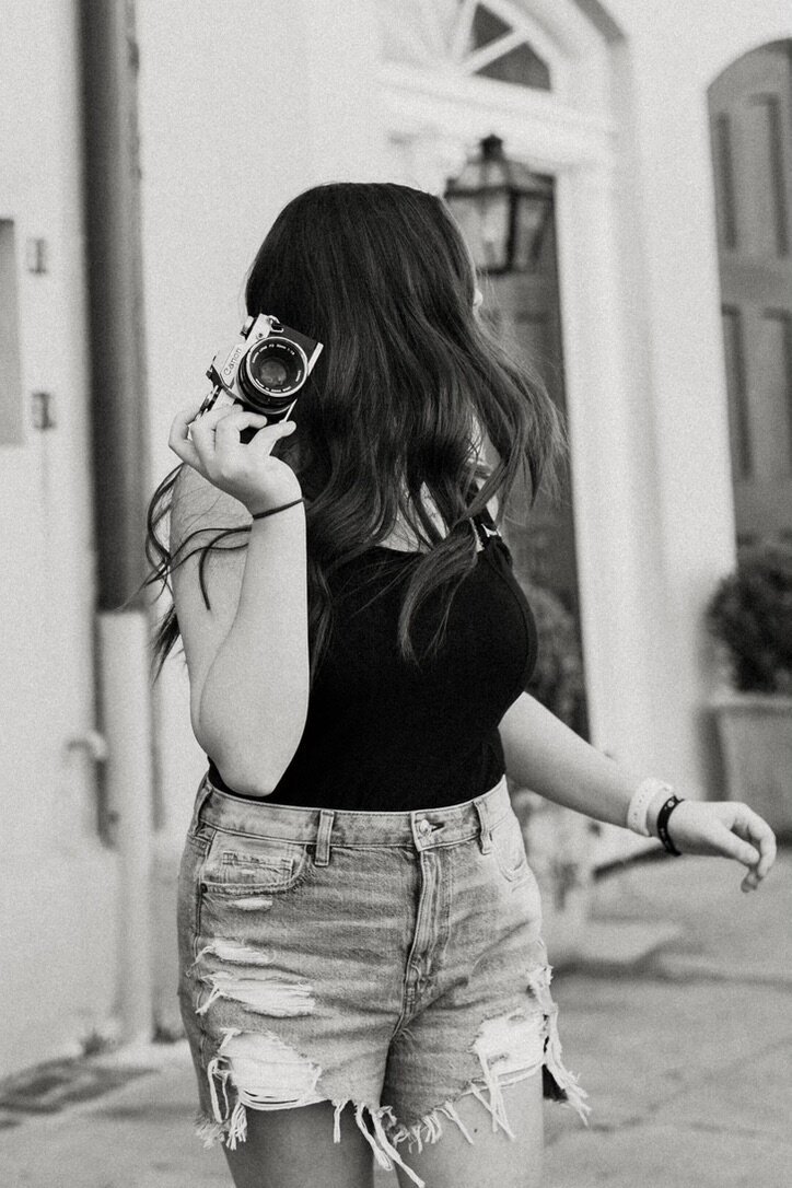 Black and white photo of Samantha with her camera looking away from the camera