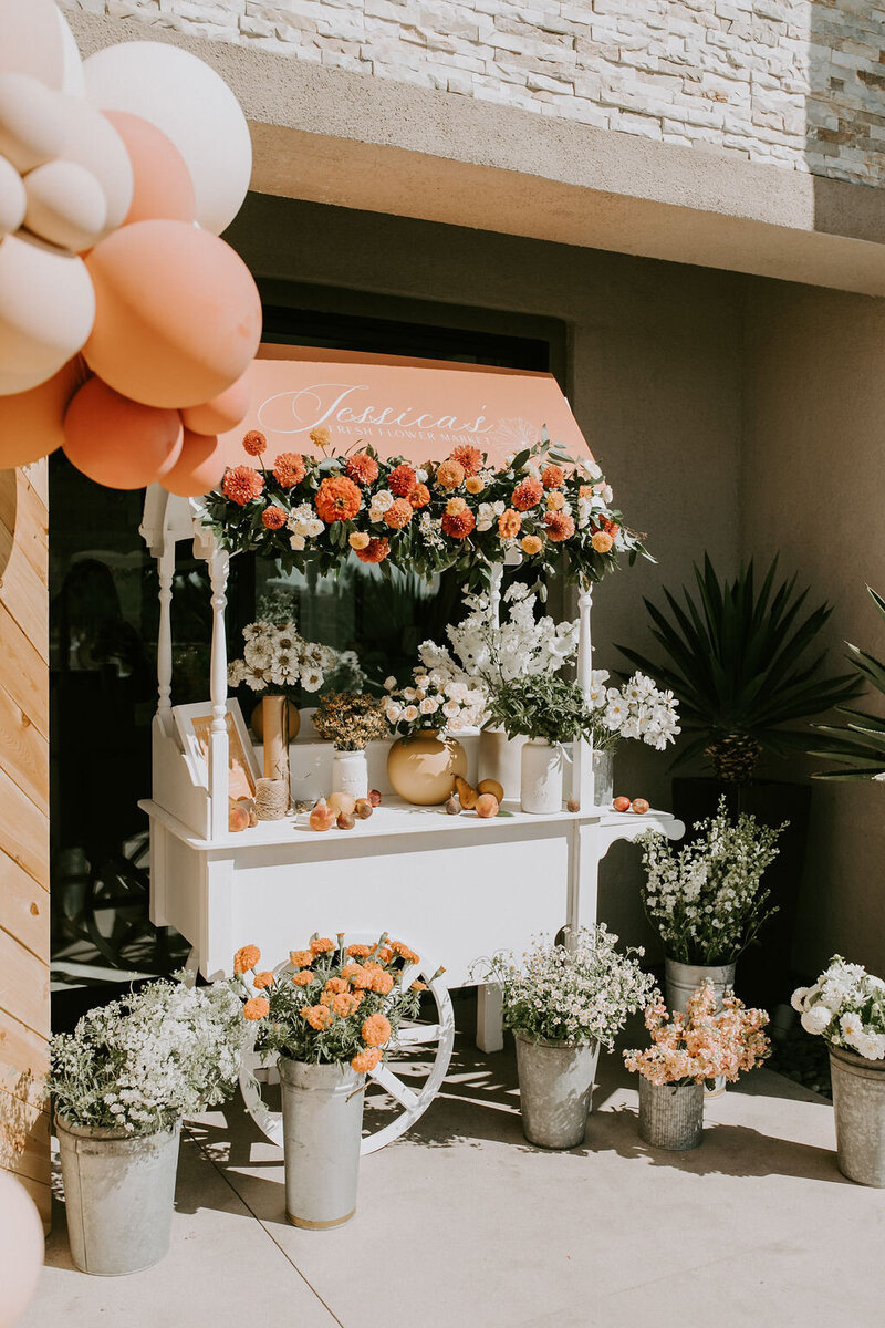 white cart covered and surrounded by white and orange flowers