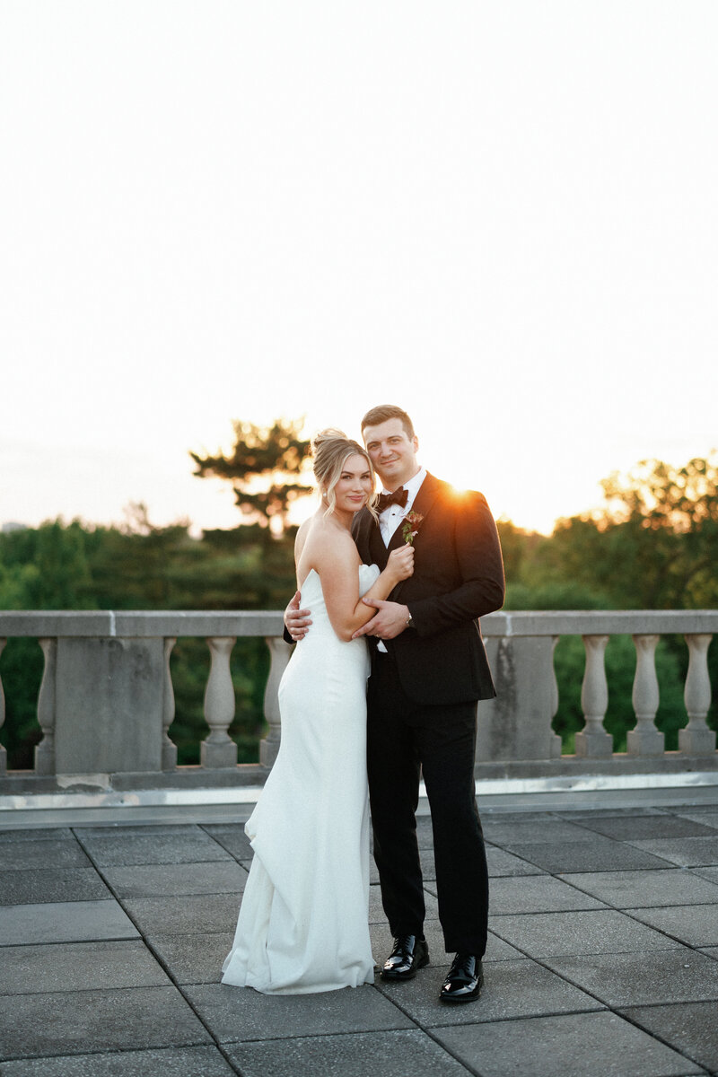 Bride and groom during golden hour on an outdoor terrace, surrounded by warm, romantic lighting.