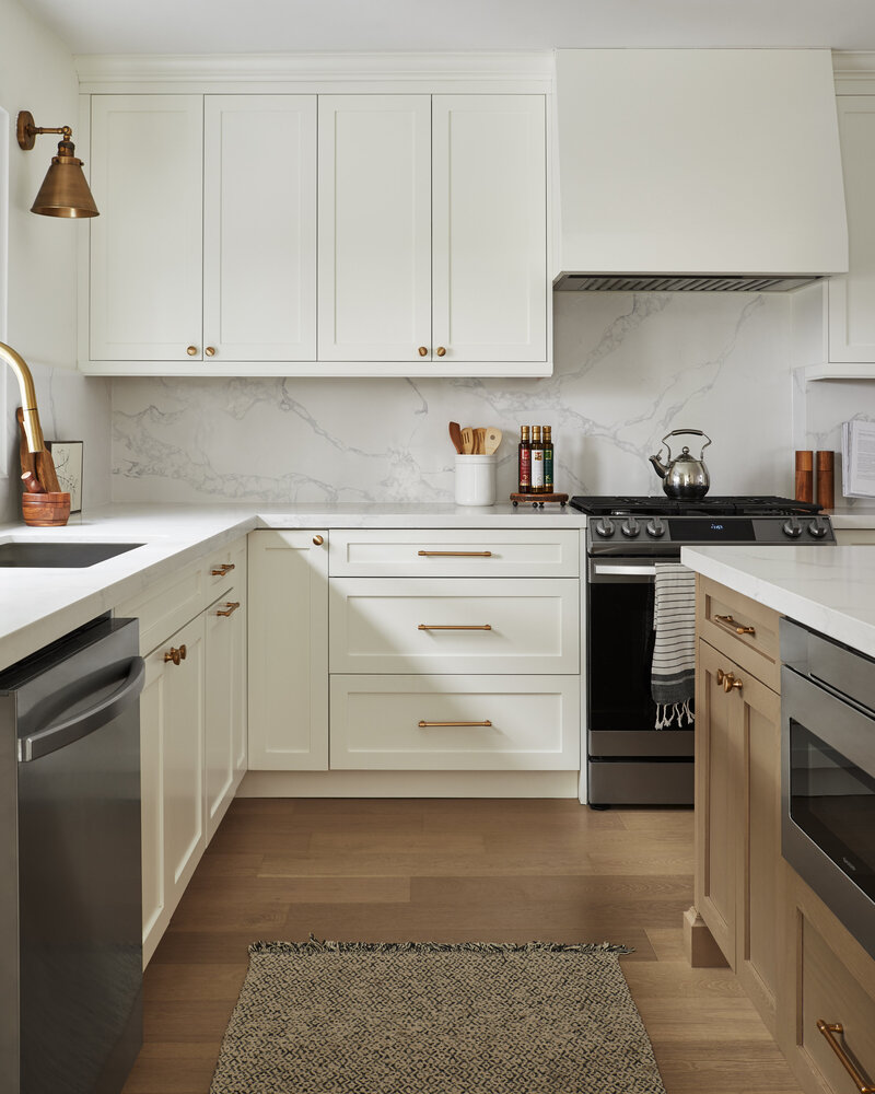 Kitchen with both wood and solid white cabinets, gas stove, and exhaust matching the cabinets. All gold hardware.