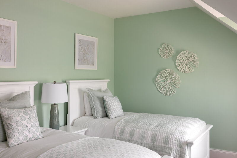 Peaceful bedroom featuring light green walls, white bedding, and decorative wall art, creating a calm and cozy atmosphere