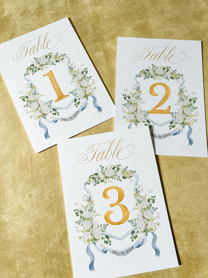A set of 15 wedding table number cards featuring the client's wedding crest by Alicia Betz of The Welcoming District.