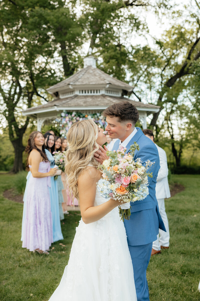 A groom dipping his bride in front of fall colored trees.
