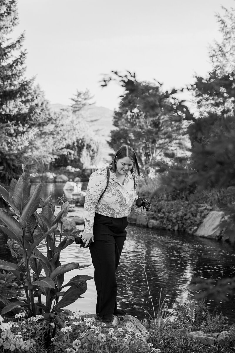 Shannon of West of Yonge Wedding Photography in Toronto walking by the water holding a camera