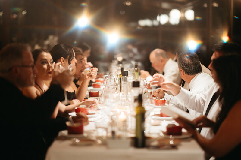 Elopement Reception Ideas | Long table with the guests of a Tuscany elopement having dinner together with sparkling lights above them 