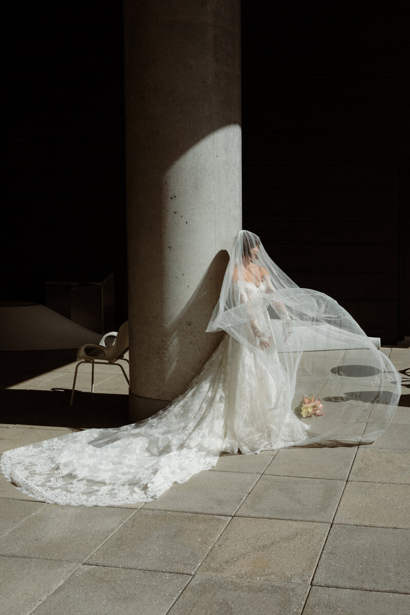Bride covered by a veil in the sun in an industrial exterior terrasse setting