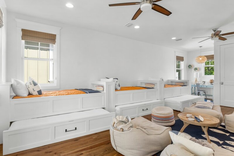 Bright bunk room with additional trundles, anchor-themed pillows, and a kids' workspace at beach rental near Panama City Beach.
