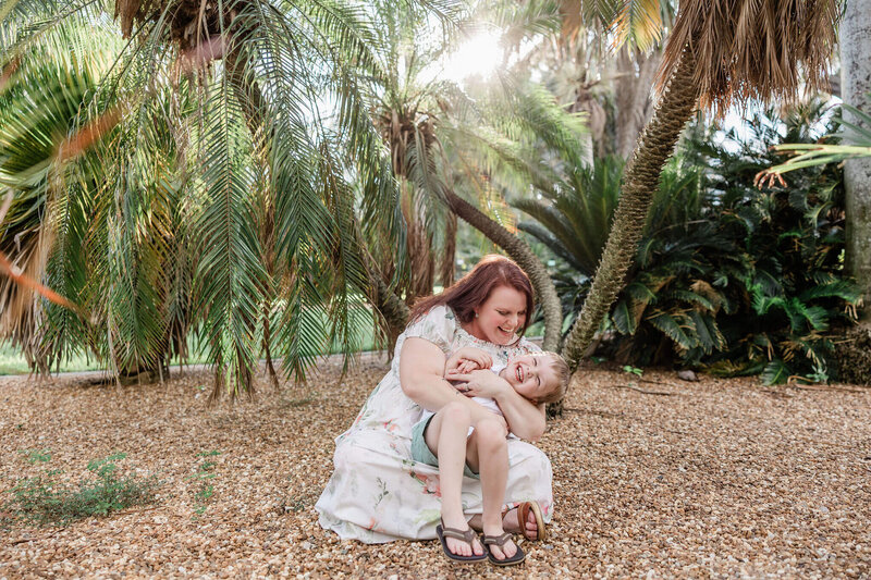 mother embraces son during family photo shoot in St. Pete, FL at Gizella Kopsick Palm Arboretum