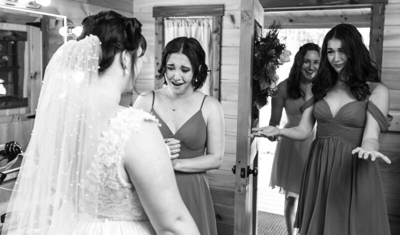 Bride's sisters react emotionally to seeing their sister in her wedding dress at Majestic Woods wedding