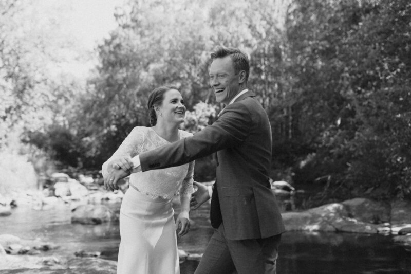 Bride and groom dancing by the river and laughing in Finland