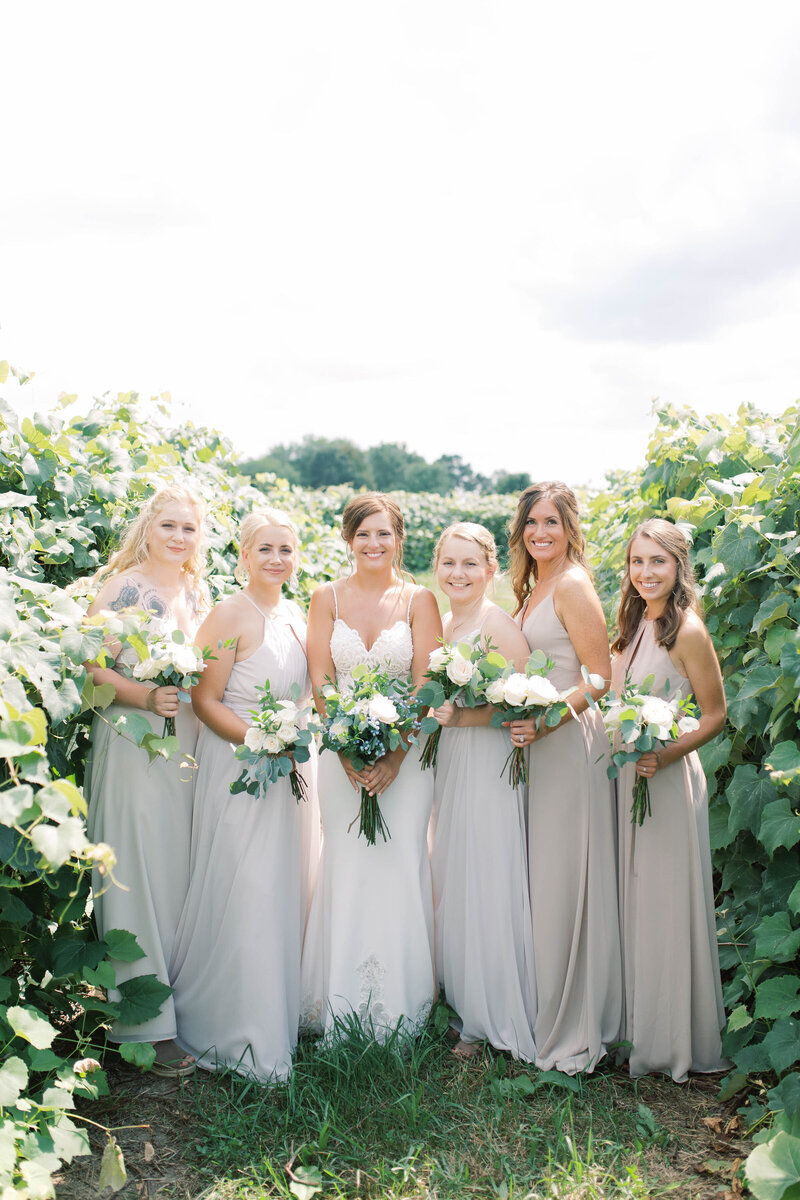 Kayla and her bridesmaids pose for a formal portrait in a vineyard, photo by Cynthia Mae Photography Grand Rapids Wedding Photographer
