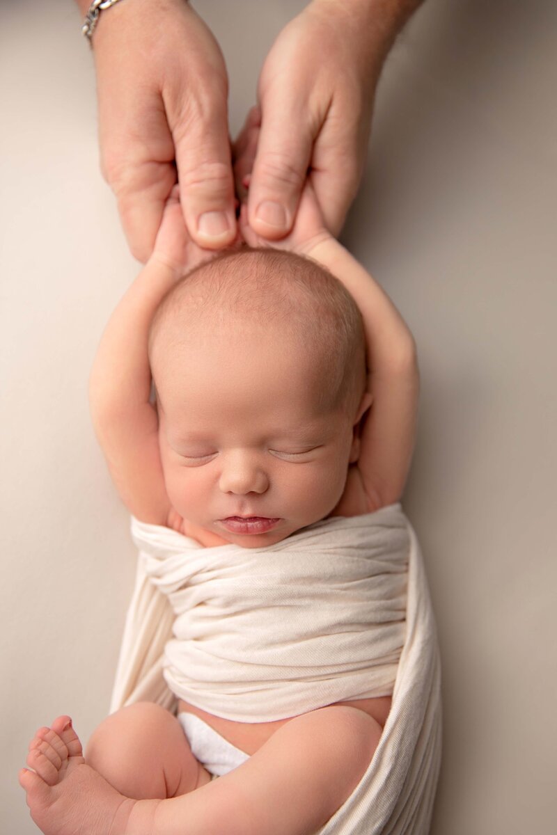 Newborn wrapped in soft cream tones, providing a timeless and elegant newborn photography session in Arizona.