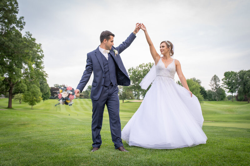 wedding couple look at one another while bride spins in her gown