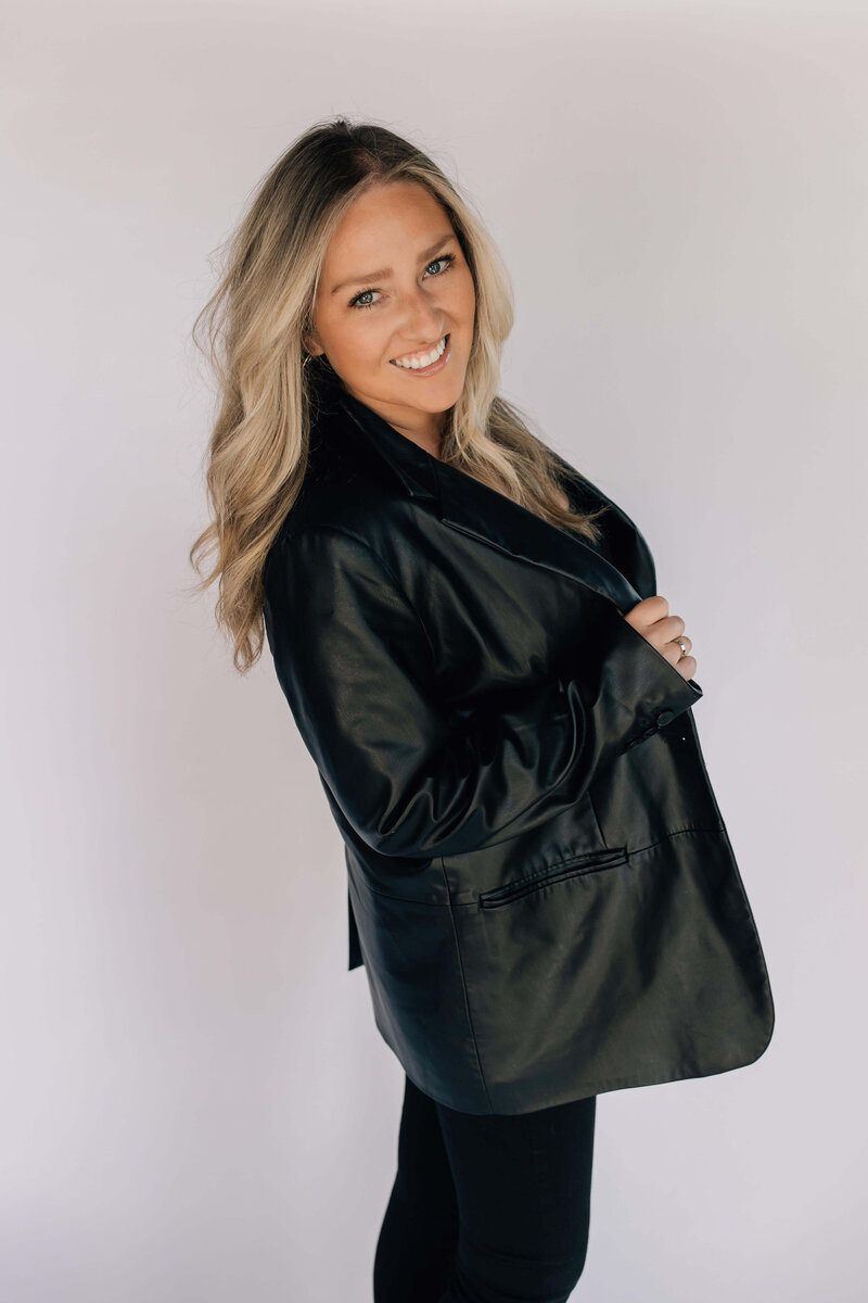Headshot of certified hair stylist with blond hair extensions smiling wearing black