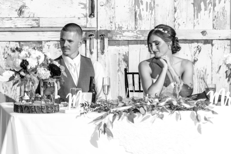 A bride and groom listen as a toast is said in their honor.