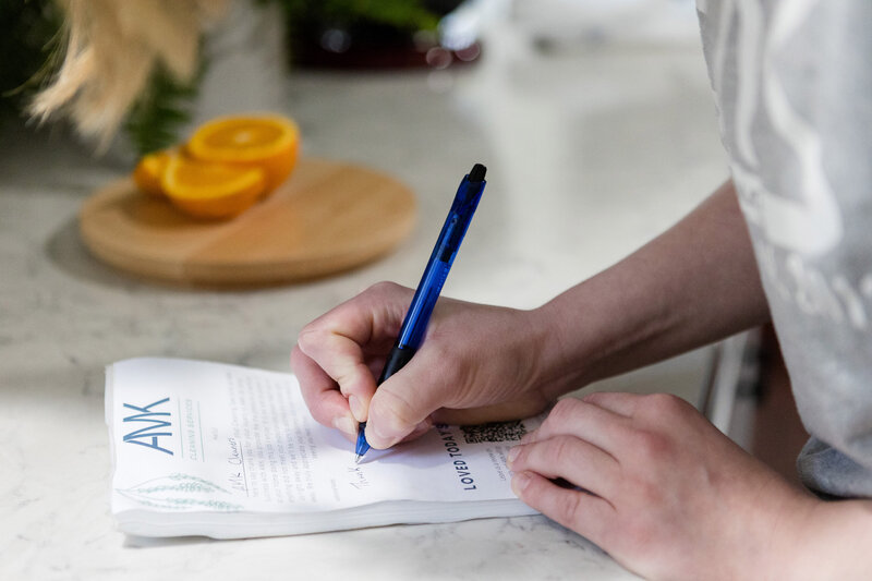 Cleaner leaving client a note on an AMK branded note pad