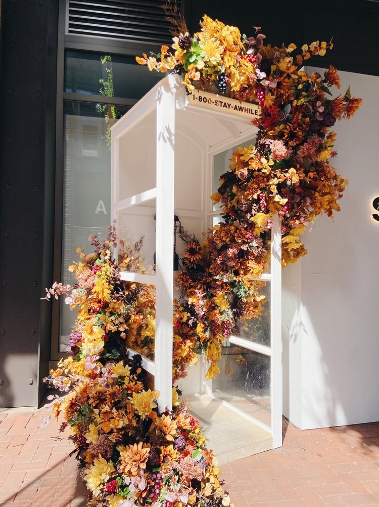 Fall phone booth floral installation. Retail shopping floral installation with autumn colors and silk florals. Design by Rosemary and Finch in Nashville, TN.