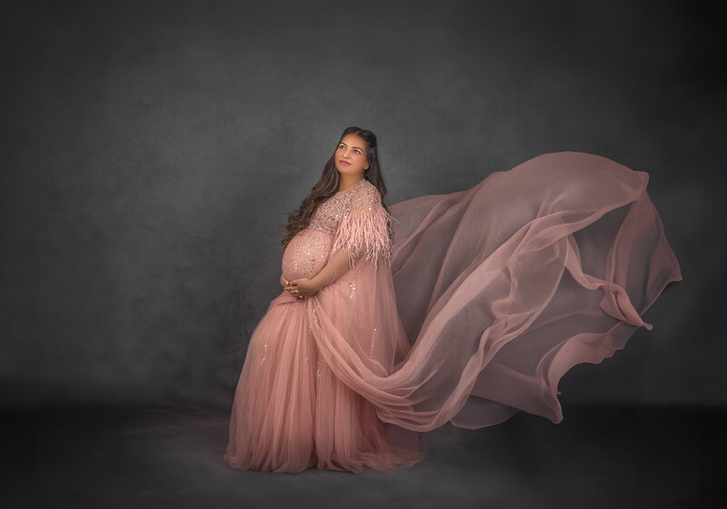 "Pregnant mom  with a dramatic fabric toss, elegantly capturing the flowing gown in a stunning maternity photography session in Ottawa."