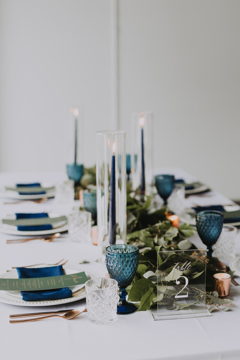 Wedding décor in the Rockies with copper chargers, navy napkins, and crystal glassware styled for a Canmore reception.