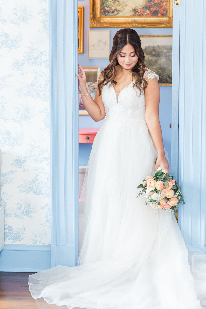 Bride holding peach bouquet standing in doorway