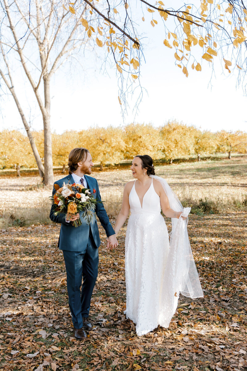 bride and groom walking in an apple orchard in Michigan Lindsay Elaine Photography