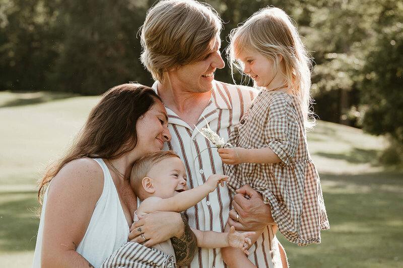 Charlotte family of four sharing sweet smiles and cuddles during a candid photography session.