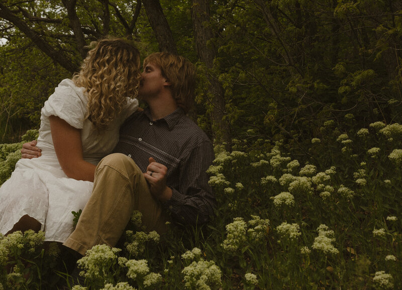 A husband and his pregnant wife walking in a grass field in Idaho Falls, ID.