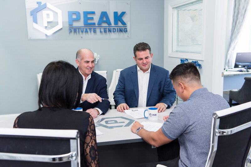 4 people sitting in a conference room talking and looking through private lending paperwork at the Peak Private Lending office in Teaneck, New Jersey.