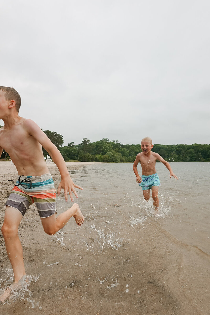 Two young boys playing on the beach in their swimsuits