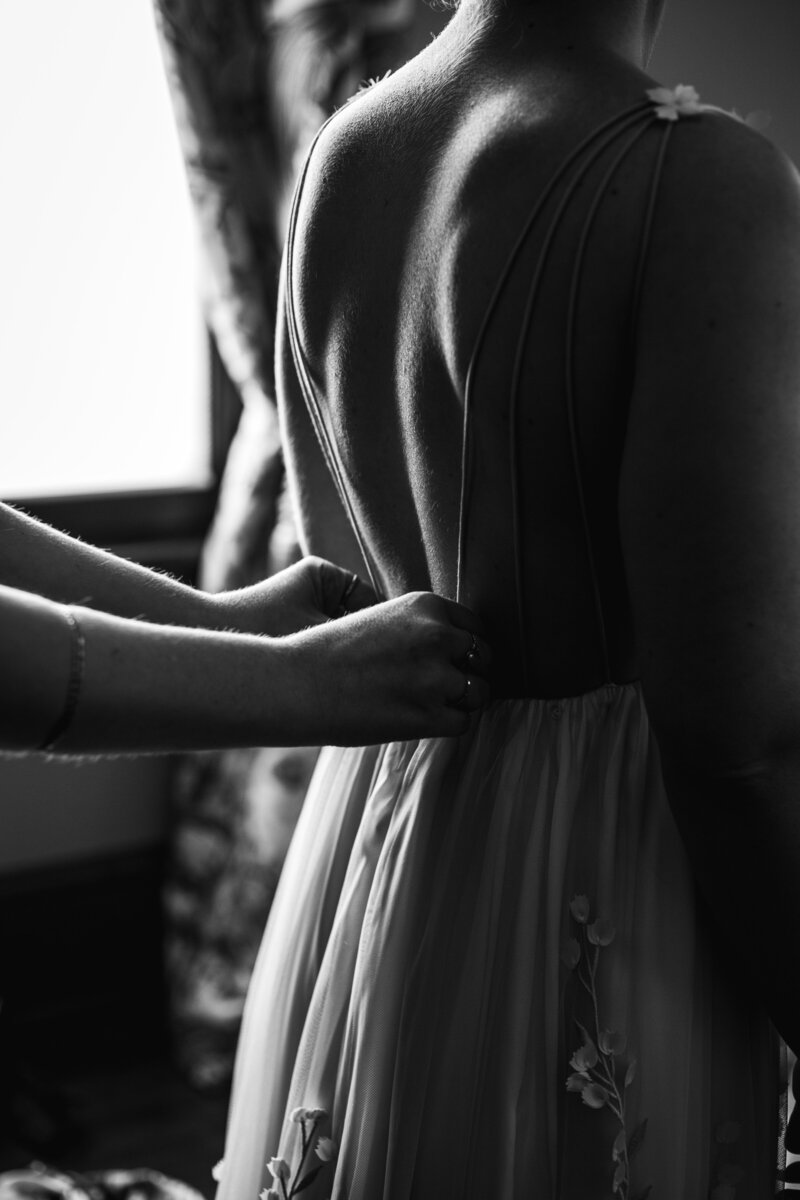 woman helping button bride's wedding dress