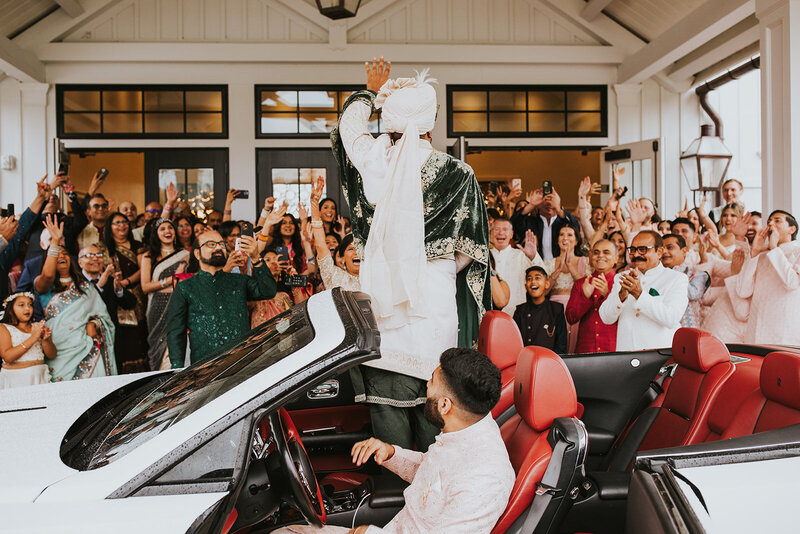 Indian Wedding Entrance, Vibrant Baraat wedding procession with the groom arriving in a luxury car, surrounded by energetic dancing