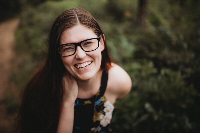 Melissa Marino, photographer, is wearing a dress and glasses, smiling happily into the camera