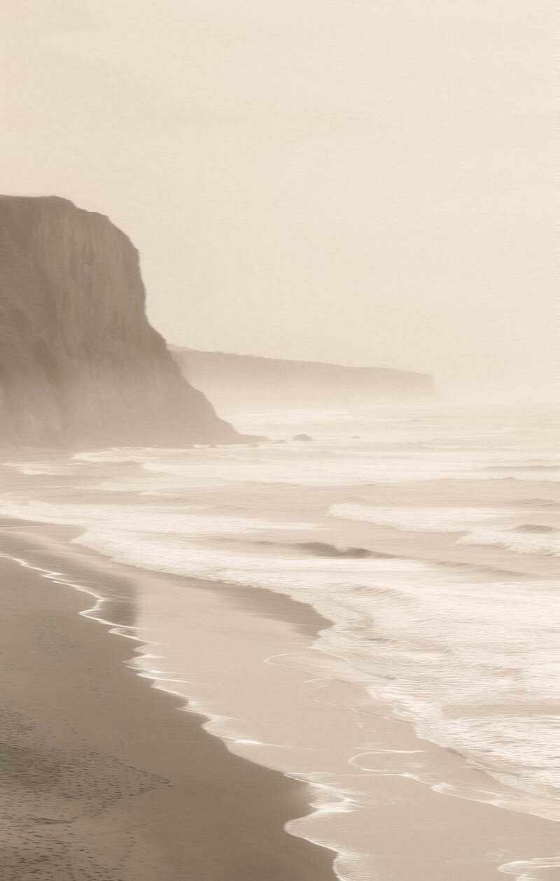large ocean cliffs meeting the frothy ocean waves on a misty day