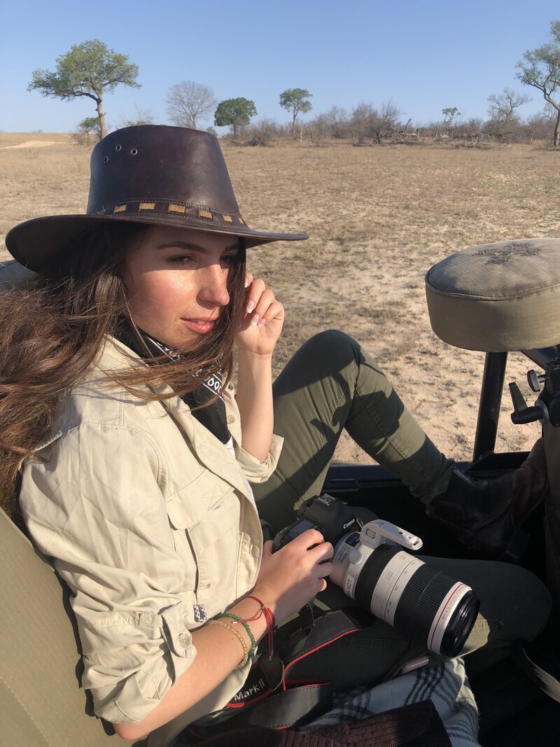 Nicole seated in a safari vehicle with camera gear, capturing wildlife and curating luxury travel experiences.